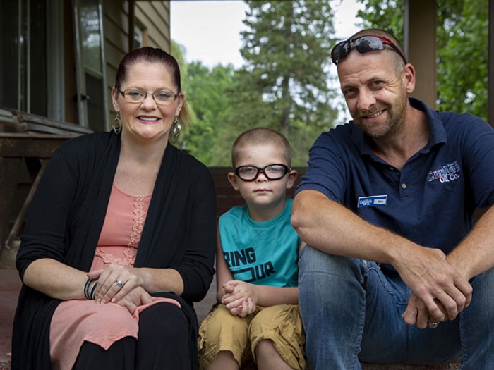 Zion sitting on steps outside his home with his parents.