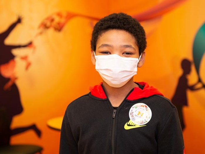 child in hospital with mask on and orange background