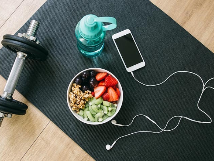 image of weight phone headphones bowl of fruit and water bottle.