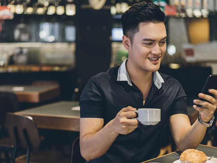 Man drinking coffee and looking at cell phone