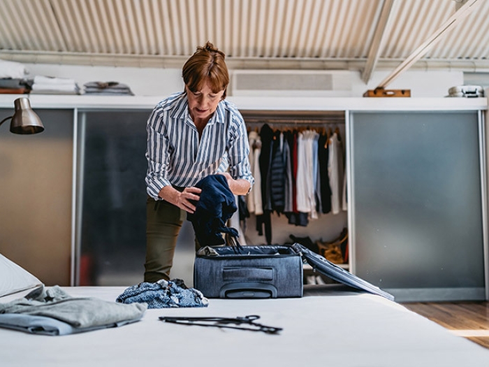 woman packing over bed in striped blue and white shirt