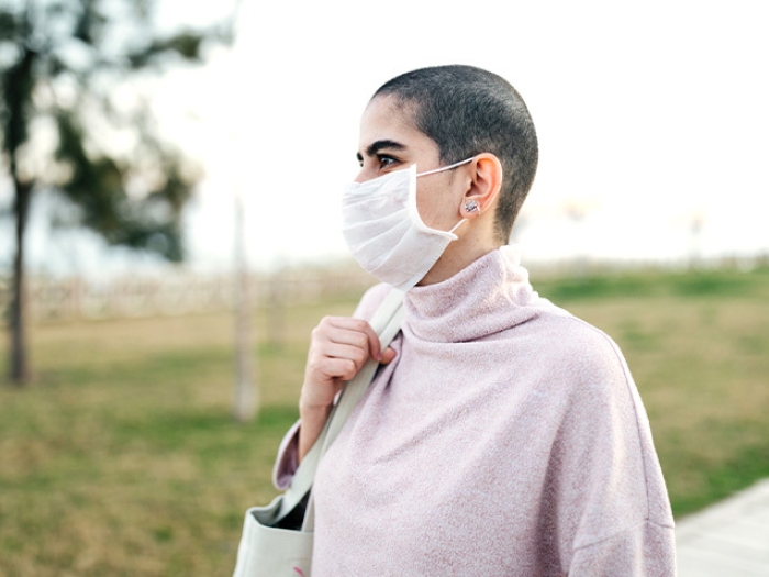 woman standing mask in pink shirt outside