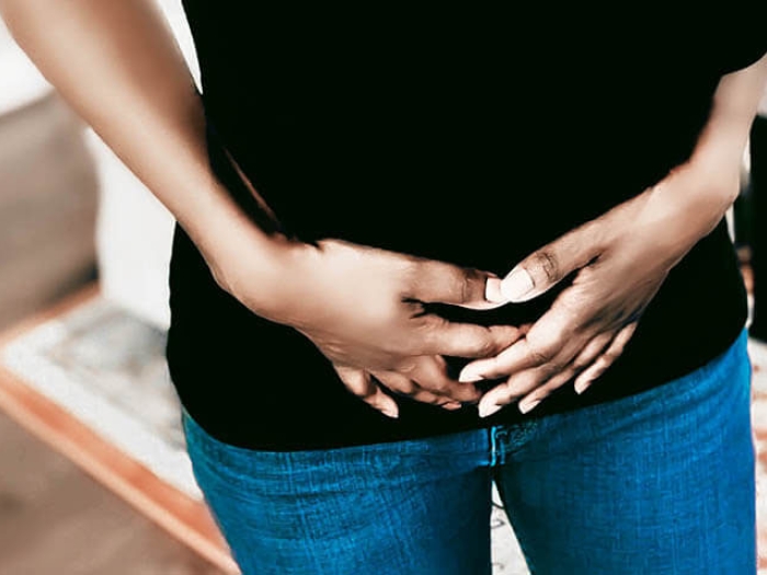 Women holding hands on lower front torso with pain