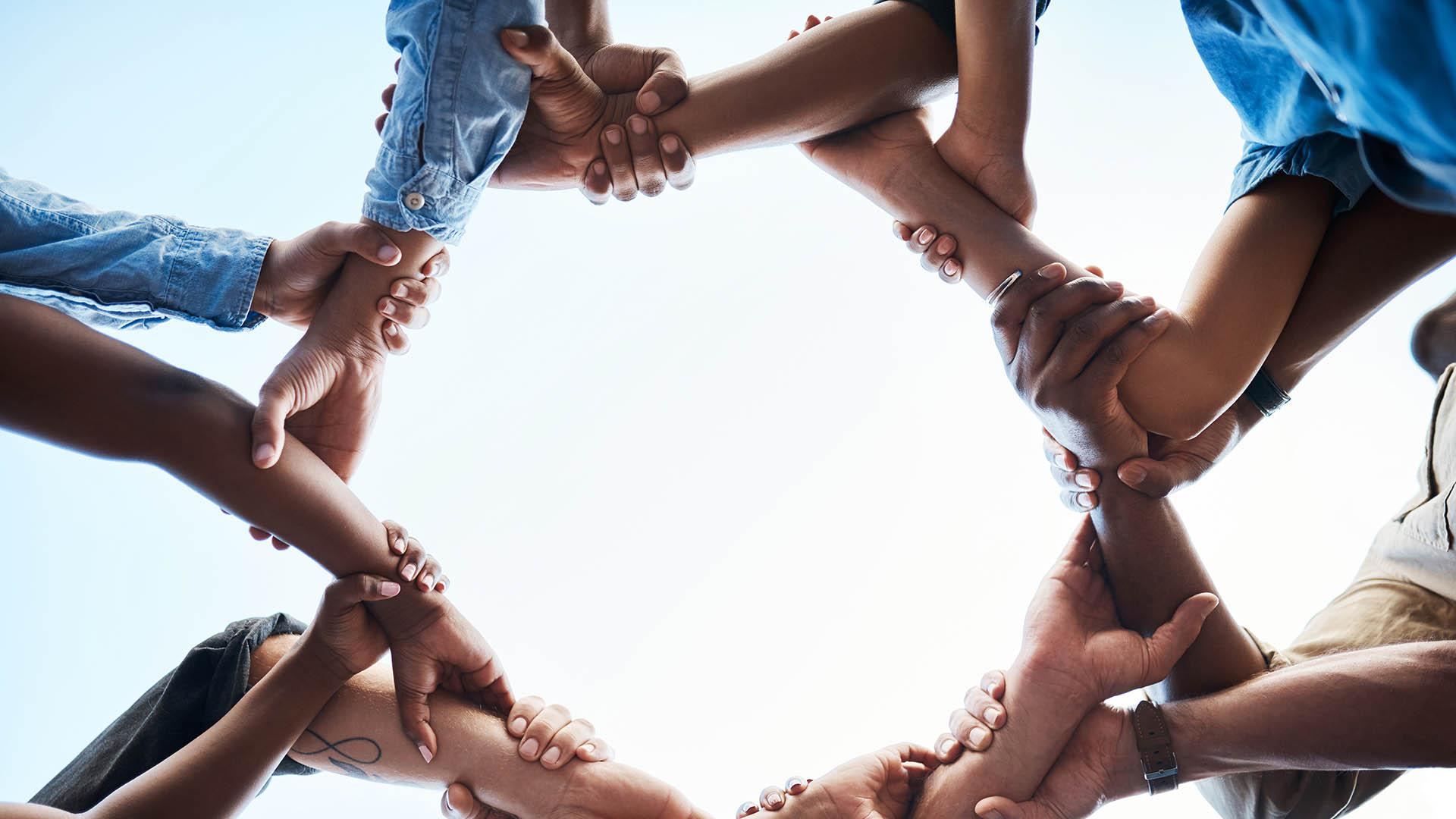 Unidentifiable people holding hands in a circle
