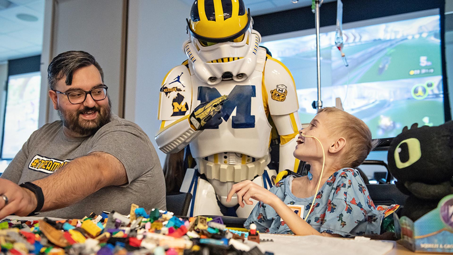 male patient in wheelchair looking up at a person dressed in a star wars costume