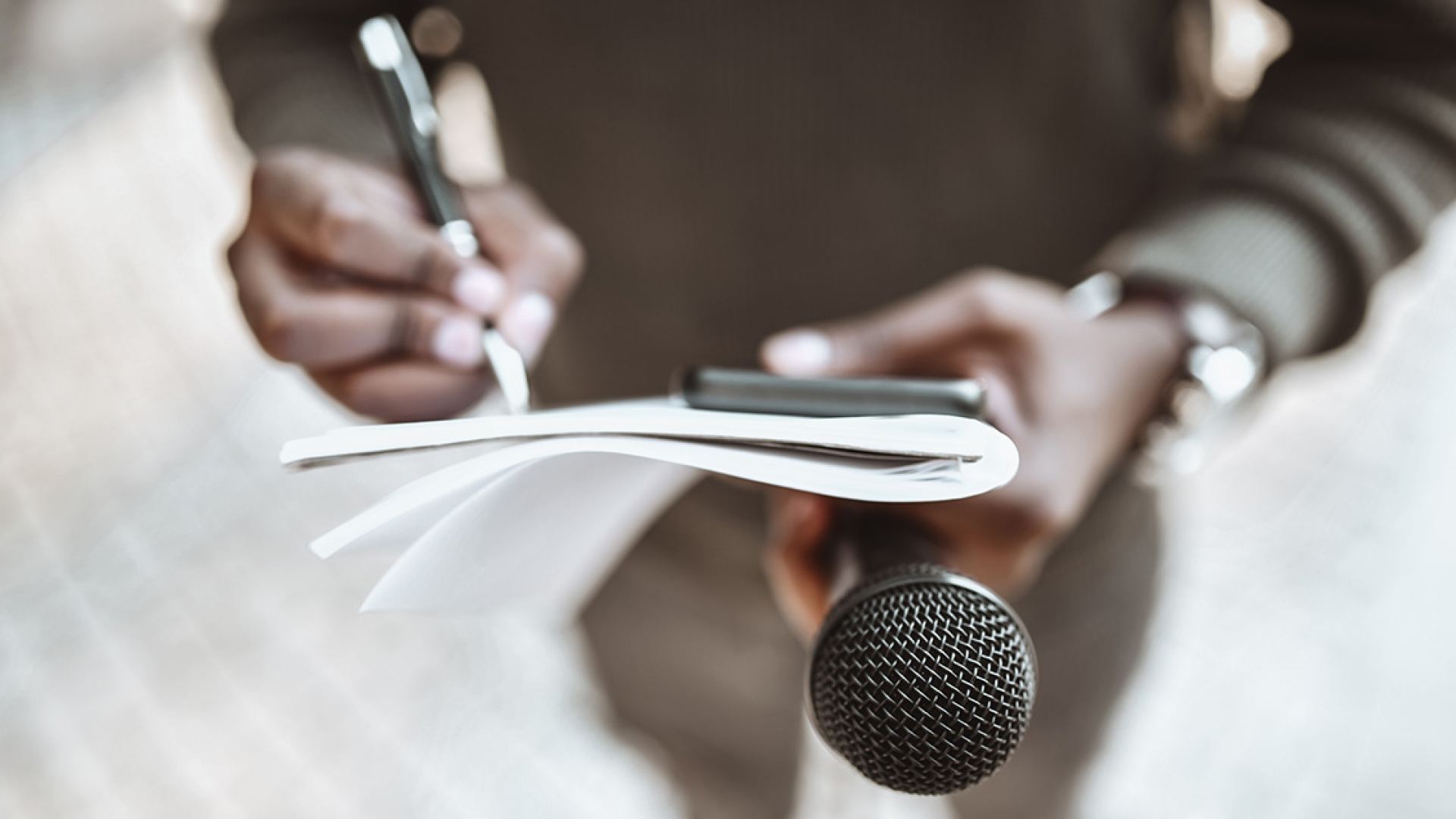 Journalist writes on notebook while holding microphone