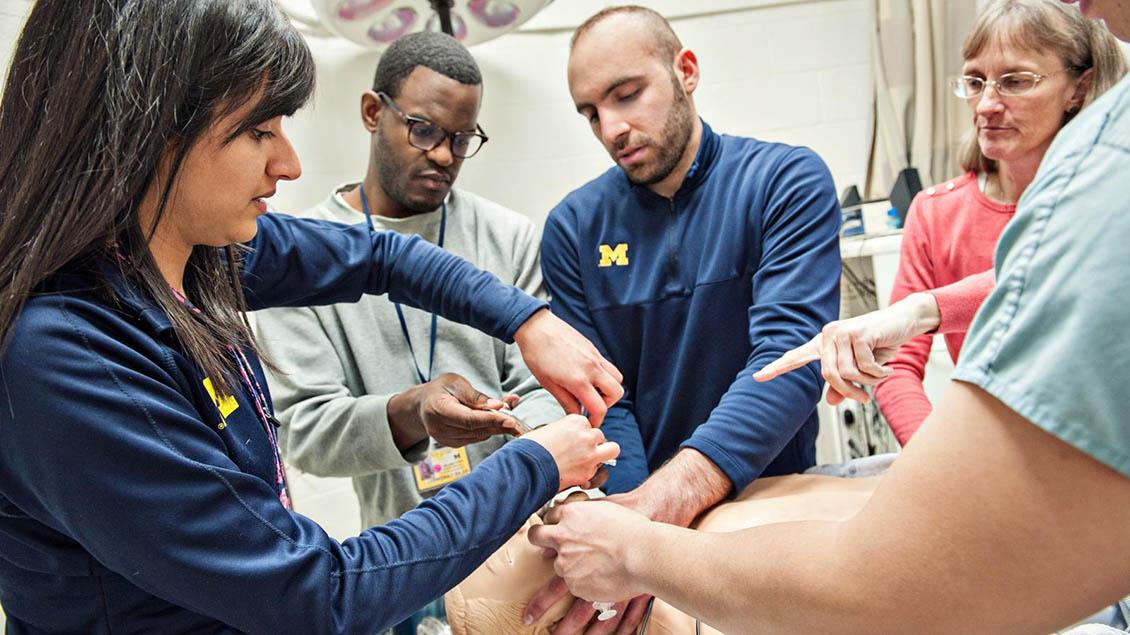 Group of students practicing on medical dummy