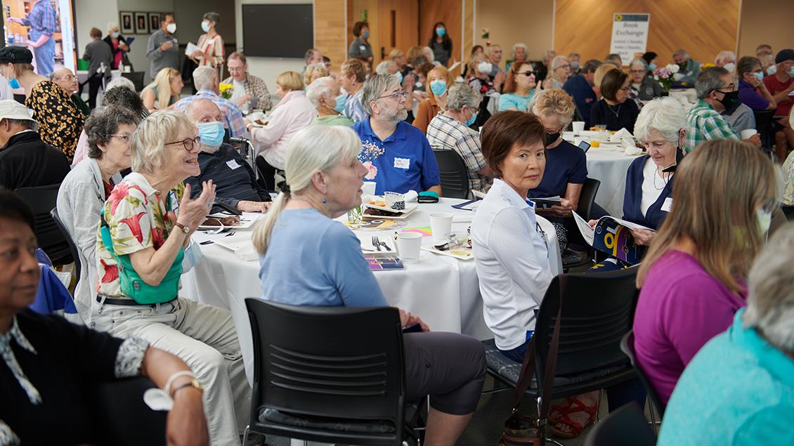 Group of elderly people sitting at a round table.