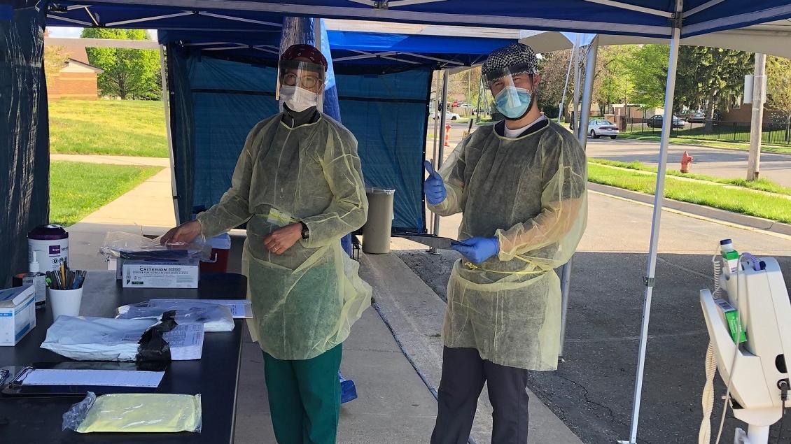 Healthcare workers in PPE kit smile for the camera.