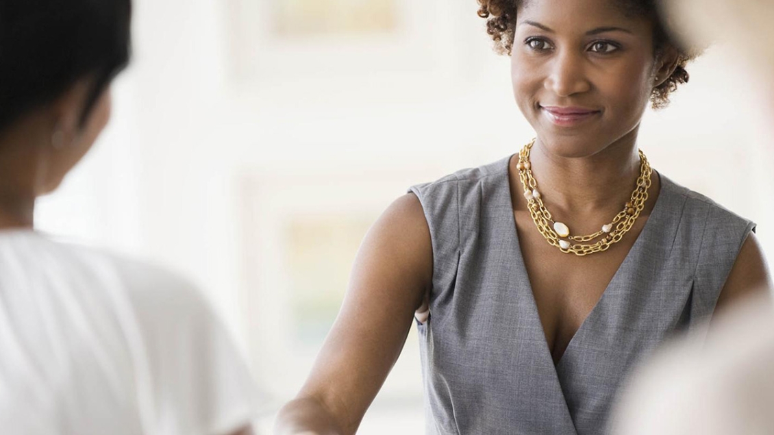 Young Black woman handing paper to another person