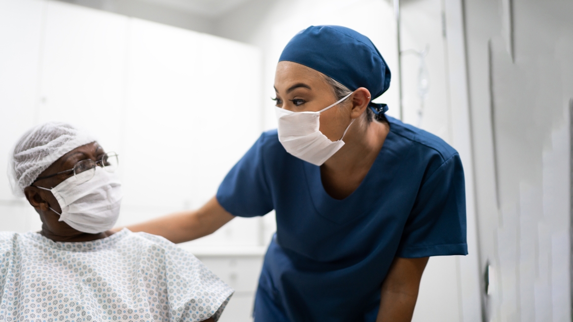 Female health care professional in blue scrubs with older Black male patient
