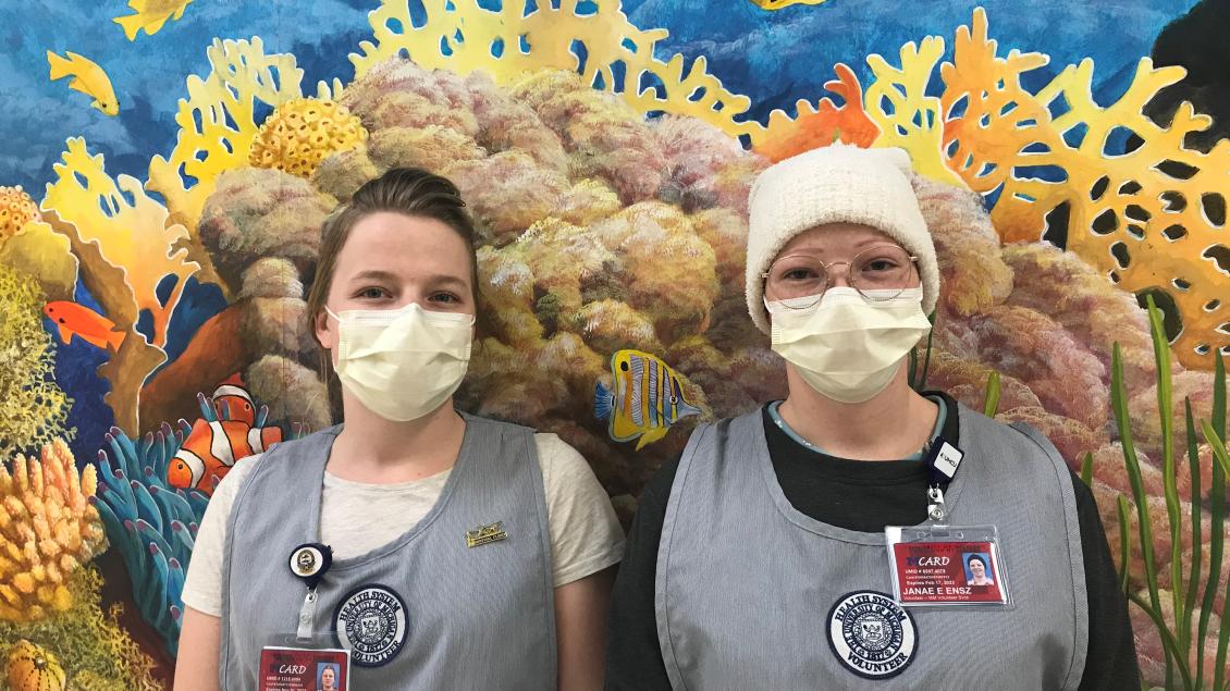 Volunteers standing against seascape background, one blocked