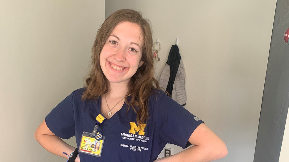 Young woman wearing navy blue scrubs smiling with hands on hips