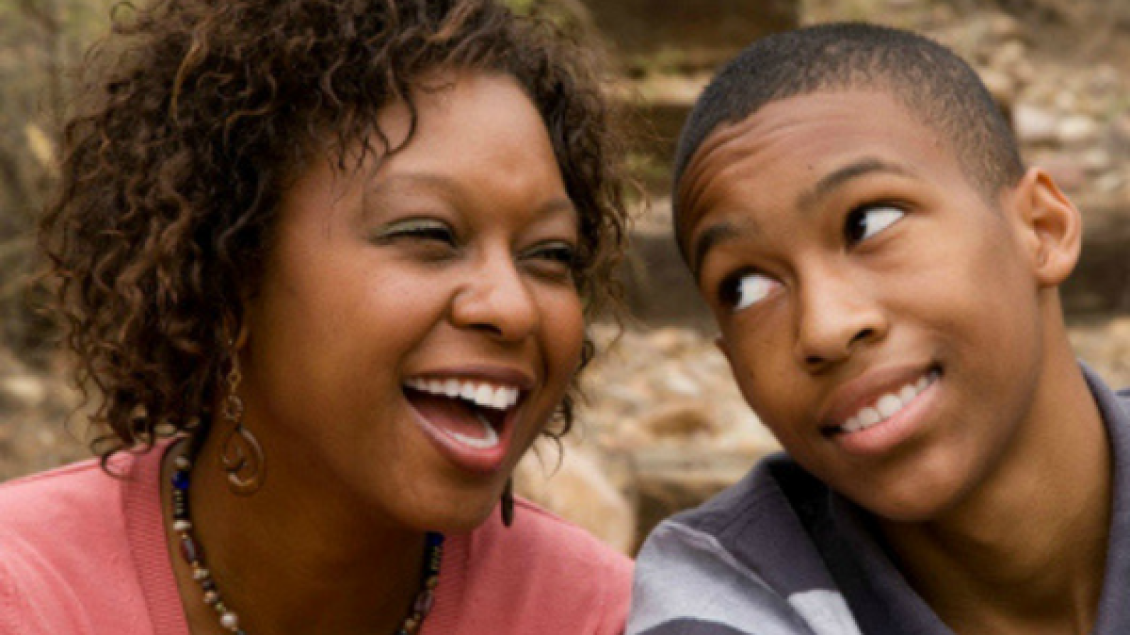 A girl is smiling while a boy looks at her candidly.