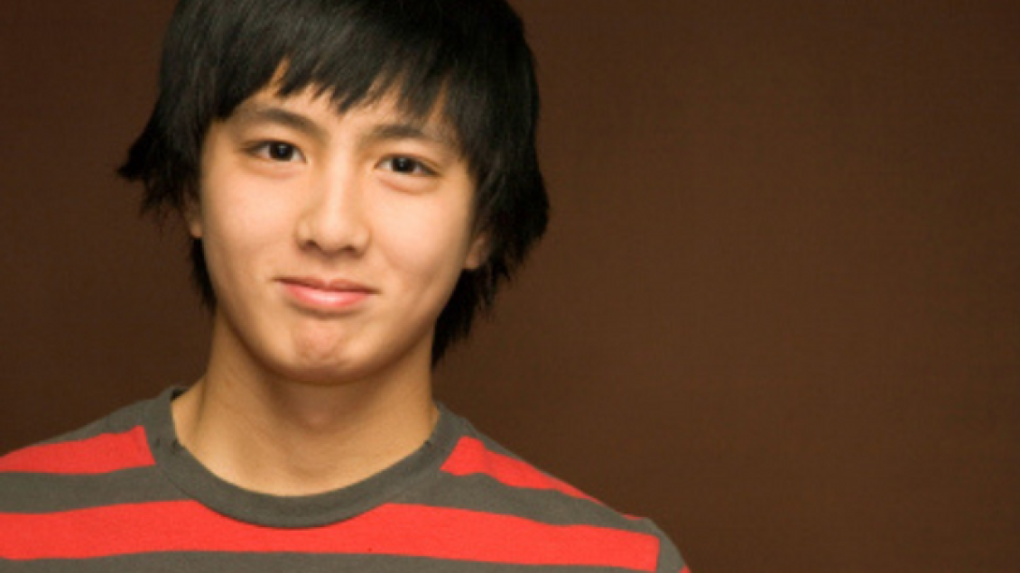 A boy wearing red and gray t-shirt smiles for the camera.
