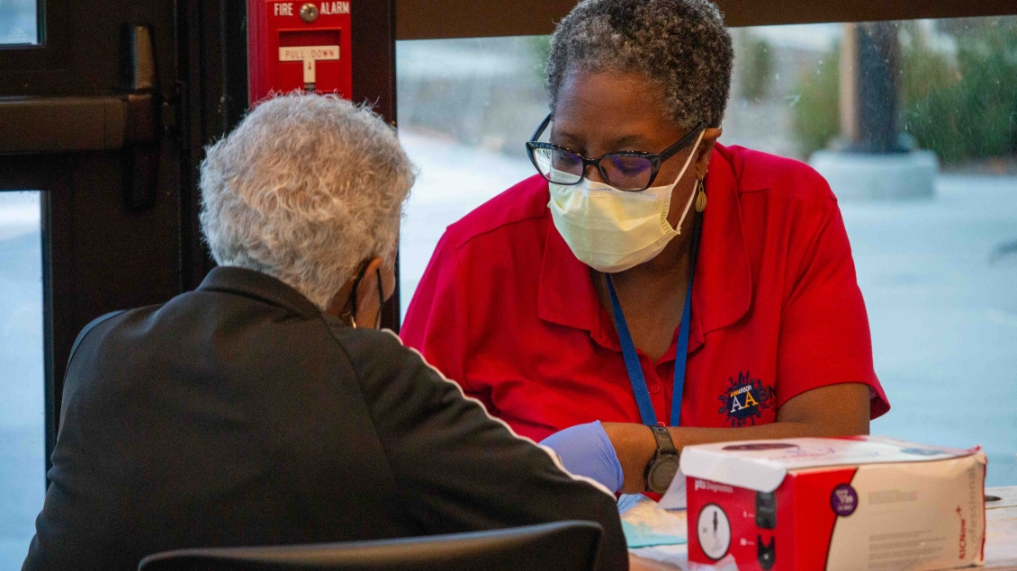 Elderly patient checks in at flu clinic table