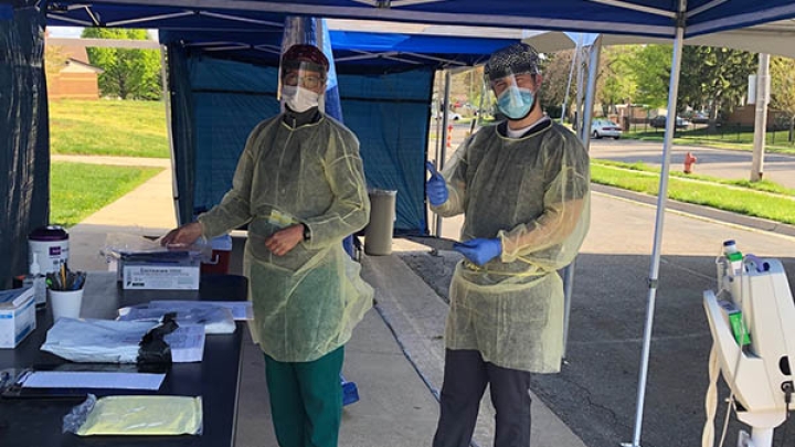 Healthcare workers wearing PPE kit smiles for the camera.