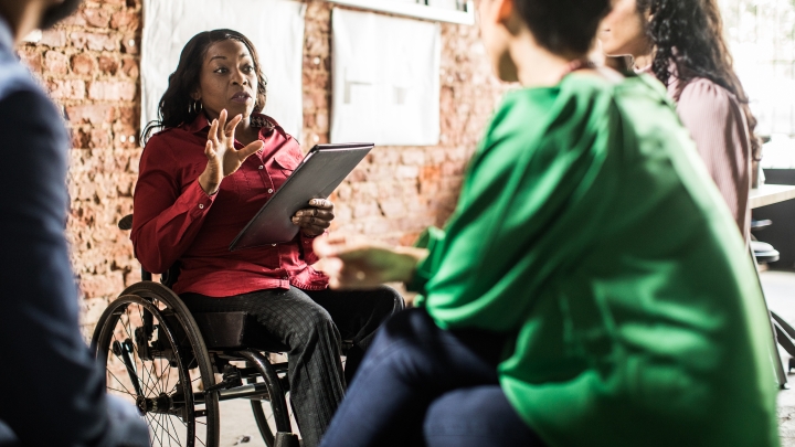 Black woman in wheelchair talking to group
