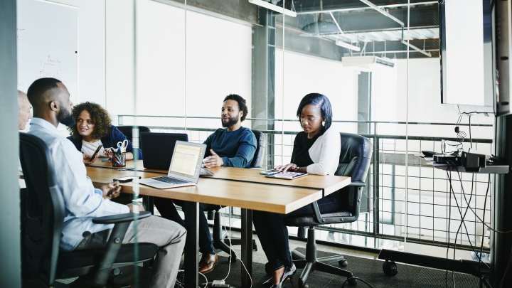 Black students talking at study table with laptop