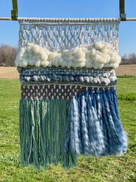 A weaved art piece hangs outside for display