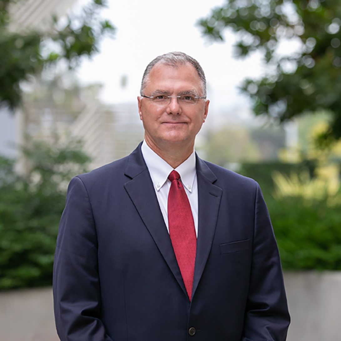 Head and shoulders shot of Eric Strucko, wearing glasses and a navy blue suit with red tie