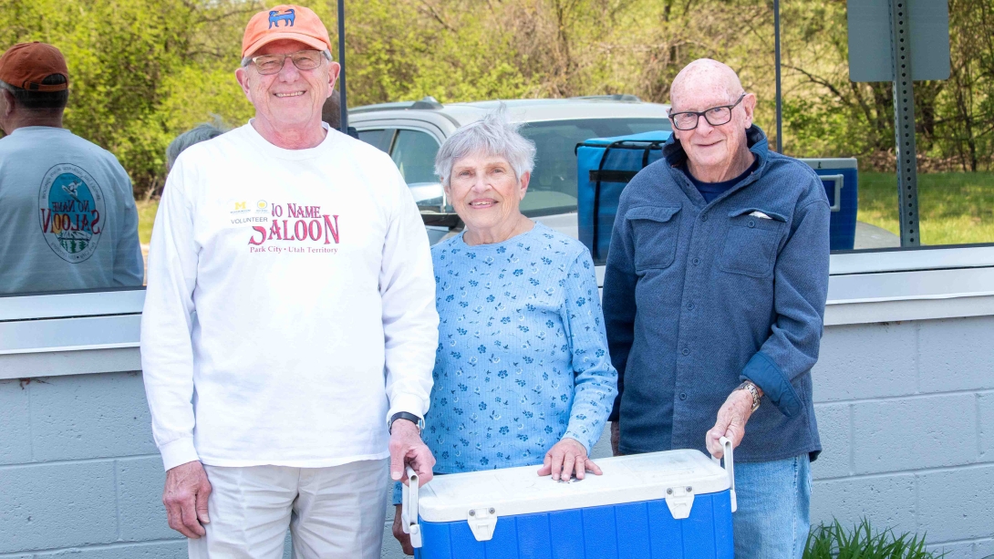 volunteers carrying large blue cooler