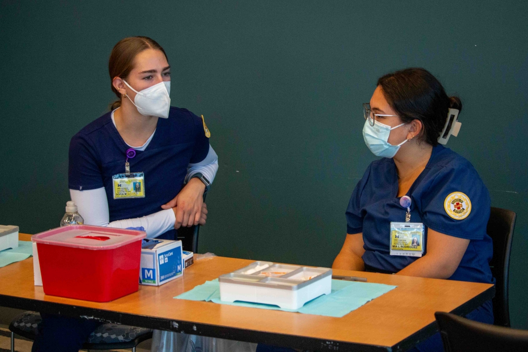 Two staff members work at table for flu clinic