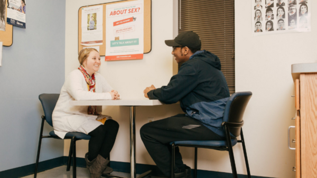 clinician speaks at table with young teen male